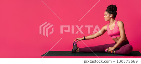 Sporty afro woman stretching on yoga mat over red studio background, panorama with free space 130575669