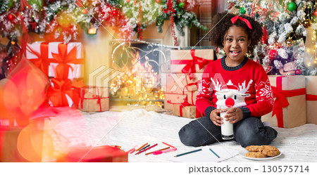Christmas snack. Cute little african american girl drinking milk and eating cookies, having break from writing letter to Santa Christmas snack. Cute little african american girl drinking milk and eating cookies, having break from writing letter to Santa 130575714