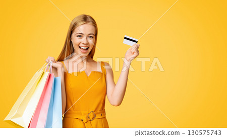 Sales And Discounts. Portrait Of Excited Young Girl With Shopping Bags And Credit Card, Standing On Yellow Background, Free Space Sales And Discounts. Portrait Of Excited Young Girl With Shopping Bags And Credit Card, Standing On Yellow Background, Free Space 130575743
