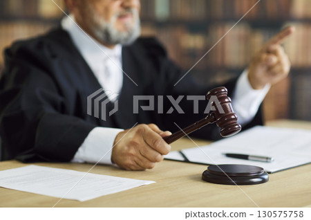 Judge striking gavel during court hearing delivering legal decision in courtroom 130575758