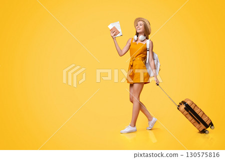 Post-Quarantine Travels. Joyful Young Girl Walking With Tickets And Suitcase On Yellow Studio Background, Panorama Post-Quarantine Travels. Joyful Young Girl Walking With Tickets And Suitcase On Yellow Studio Background, Panorama 130575816