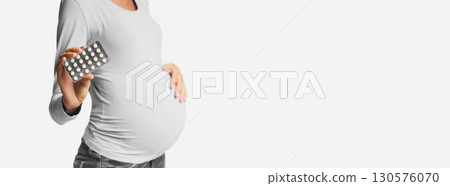 Expectant woman showing pills blister pack over white background, crop Expectant woman showing pills blister pack over white background, crop 130576070