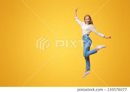 Carefree youth. Happy young girl jumping on air and smiling over orange background Carefree youth. Happy young girl jumping on air and smiling over orange background 130576077