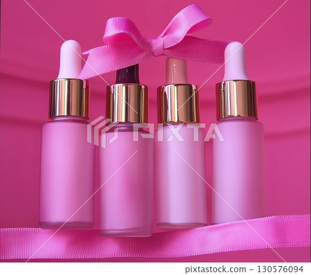 Row pink bottles oil, concentrate, serum, blank brand label, multicolored satin ribbon and gold cap pastel background, minimalist design. Cosmetics advertising concept, mockup, place text 130576094