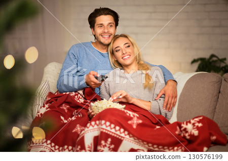Couple in love at Christmas eve enjoying popcorn and watching tv at home Couple in love at Christmas eve enjoying popcorn and watching tv at home 130576199