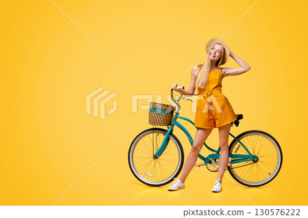 Summer Plans. Portrait Of Pensive Cute Teen Girl Standing Next To Vintage Bike Over Yellow Background, Panorama With Copy Space Summer Plans. Portrait Of Pensive Cute Teen Girl Standing Next To Vintage Bike Over Yellow Background, Panorama With Copy Space 130576222