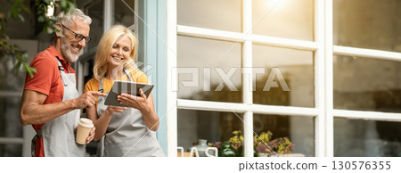 Modern Technologies. Smiling Mature Farmers Couple In Aprons Using Digital Tablet Together And Drinking Coffee While Standing At Terrace Near Country House, Happy Spouses Browsing Internet, Copy Space Modern Technologies. Smiling Mature Farmers Couple In Aprons Using Digital Tablet Together And Drinking Coffee While Standing At Terrace Near Country House, Happy Spouses Browsing Internet, Copy Space 130576355