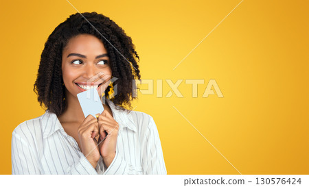 Shopaholic. African american woman holding plastic credit card, dreaming about new clothes and phone, copyspace Shopaholic. African american woman holding plastic credit card, dreaming about new clothes and phone, copyspace 130576424