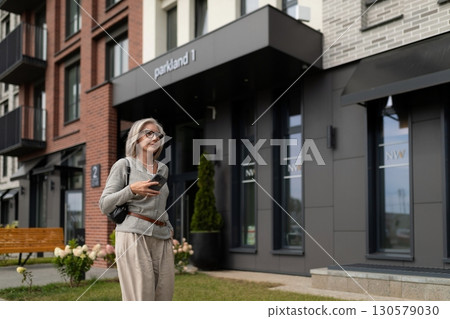 Modern woman enjoying a stroll outside a contemporary building in an urban area during daytime Modern woman enjoying a stroll outside a contemporary building in an urban area during daytime 130579030