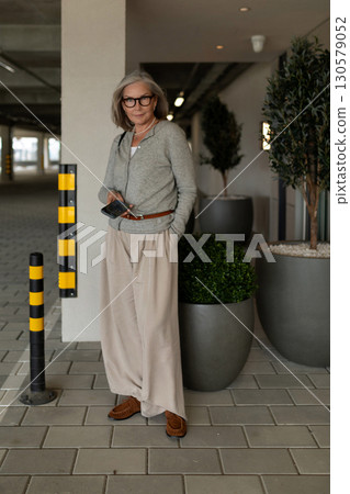 Stylish senior woman poses confidently in modern parking garage with contemporary planters Stylish senior woman poses confidently in modern parking garage with contemporary planters 130579052