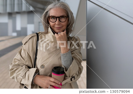 Stylish woman enjoying coffee at urban location in fall afternoon, showcasing modern fashion and Stylish woman enjoying coffee at urban location in fall afternoon, showcasing modern fashion and 130579094