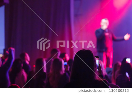 Silhouettes of audience during live performance with vibrant lighting on stage Silhouettes of audience during live performance with vibrant lighting on stage 130580213