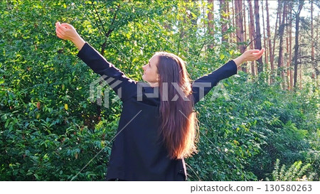 young woman with arms outstretched. scene captures a sense of freedom, serenity, connection to nature. Young woman in office clothes is standing in middle of natural landscape. Concept of fatigue, off young woman with arms outstretched. scene captures a sense of freedom, serenity, connection to nature. Young woman in office clothes is standing in middle of natural landscape. Concept of fatigue, off 130580263