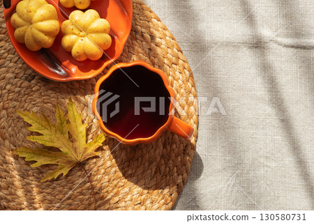 Pumpkin Mug and Mini Cakes with Autumn Leaf on Woven Placemat 130580731