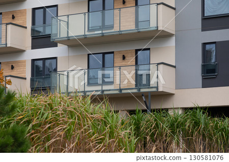 Modern high-rise apartment buildings in a residential area with balconies and greenery nearby 130581076