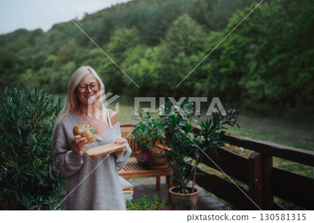 Elderly woman having lunch on terrace. 130581315