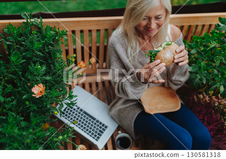 Elderly woman having lunch while working from homeoffice. 130581318