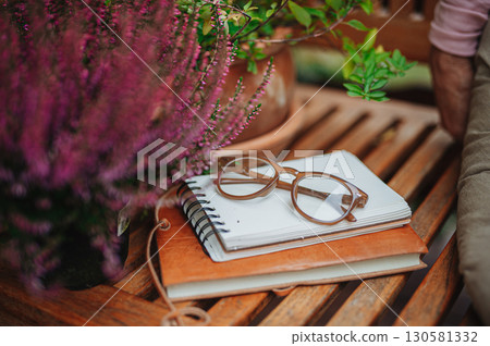 Reading glasses resting on notebook in autumn garden 130581332