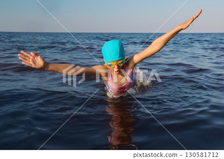 Girl swimmer 8 years old makes a swimmer's jump of sea and swimming in sunny day Girl swimmer 8 years old makes a swimmer's jump of sea and swimming in sunny day 130581712