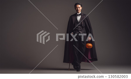 A simple background of a man standing in a vampire costume 130582003
