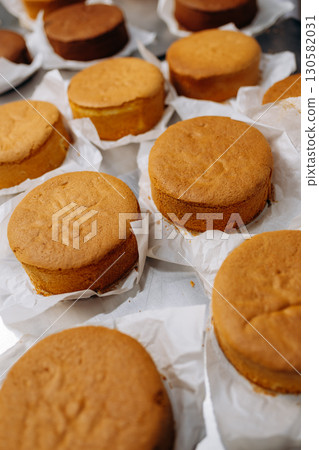 Freshly baked sponge cake layers cooling on parchment paper in a professional bakery kitchen Freshly baked sponge cake layers cooling on parchment paper in a professional bakery kitchen 130582031