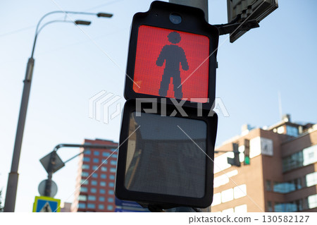 Red pedestrian traffic light in the city with a clear view of the digital display showing a person standing, indicating do not walk at busy intersection Red pedestrian traffic light in the city with a clear view of the digital display showing a person standing, indicating do not walk at busy intersection 130582127