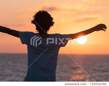 Person with Arms Stretched Out at a Sunset 130582498
