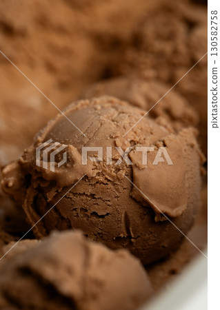 Creamy chocolate ice cream scoops close-up, rich texture and deep brown color Creamy chocolate ice cream scoops close-up, rich texture and deep brown color 130582758