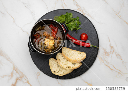 Traditional Georgian khashlama stew with beef, vegetables, herbs and bread on slate plate 130582759