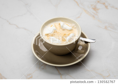 Creamy coffee with marshmallows in a beige cup on a marble background, top view 130582767