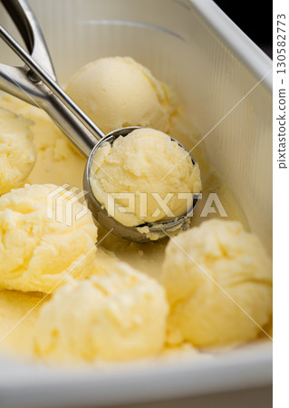 Vanilla ice cream scoops in tray with scoop utensil, close-up food background Vanilla ice cream scoops in tray with scoop utensil, close-up food background 130582773