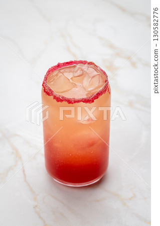 Refreshing red cocktail with ice and sugar rim in elegant glass on marble background Refreshing red cocktail with ice and sugar rim in elegant glass on marble background 130582776