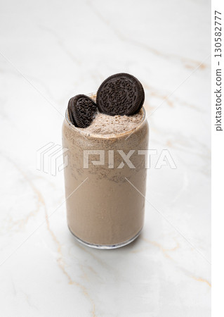 Creamy Oreo milkshake in a glass, topped with cookies on marble background Creamy Oreo milkshake in a glass, topped with cookies on marble background 130582777