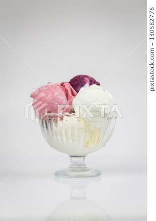 Colorful fruit ice cream scoops in glass bowl on white background, isolated dessert 130582778