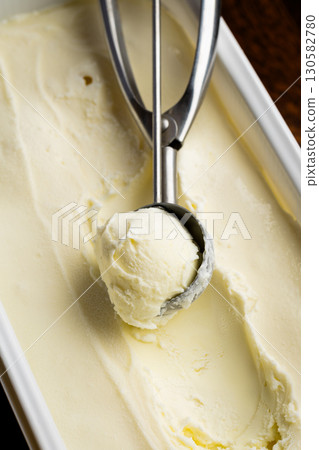 Vanilla ice cream scoop in metal spoon over creamy background, macro food texture shot Vanilla ice cream scoop in metal spoon over creamy background, macro food texture shot 130582780