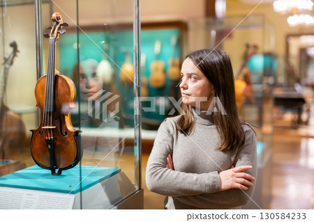 Interested brunette visiting exhibition of medieval musical instruments in museum Interested brunette visiting exhibition of medieval musical instruments in museum 130584233