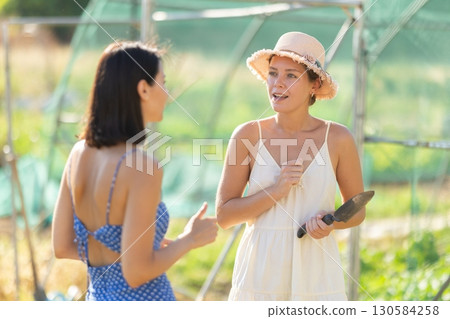 Two women talking in garden greenhouse 130584258