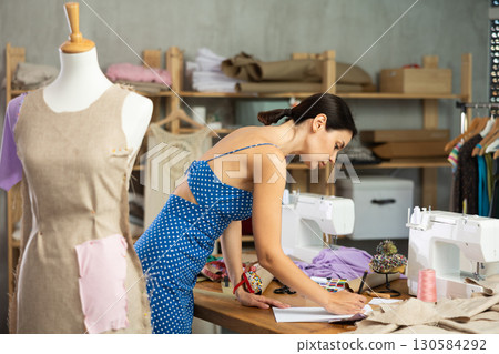 Young woman seamstress draws sketch on paper Young woman seamstress draws sketch on paper 130584292