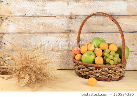 Harvest concept, Thanksgiving background, autumn composition with fruits, natural berries, apples, grapes, apricots, ears of wheat and rye, flowers on a wooden background 130584380