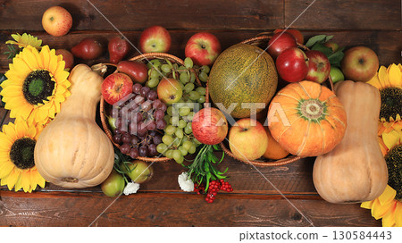 Autumn background and harvest in the village with seasonal berries, pumpkins, apples, rowan, grapes and natural flowers on a wooden background, copy space, flat lay. Happy Thanksgiving Autumn background and harvest in the village with seasonal berries, pumpkins, apples, rowan, grapes and natural flowers on a wooden background, copy space, flat lay. Happy Thanksgiving 130584443