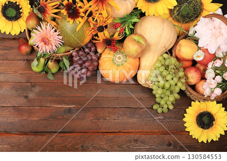 Autumn background and harvest in the village with seasonal berries, pumpkins, apples, rowan, grapes and natural flowers on a wooden background, copy space, flat lay. Happy Thanksgiving 130584553