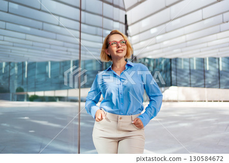Young businesswoman with glasses standing outside 130584672