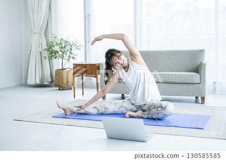 Young woman stretching while looking at a computer at home Young woman stretching while looking at a computer at home 130585585