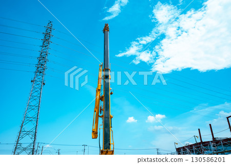 Crane arms stretching into the sky and power transmission towers c-4 light color 130586201