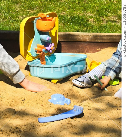 Children Playing in Backyard Sandbox with Colorful Toys 130586788