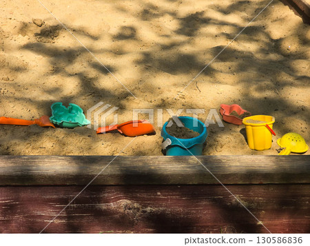 Children Playing in Backyard Sandbox with Colorful Toys 130586836