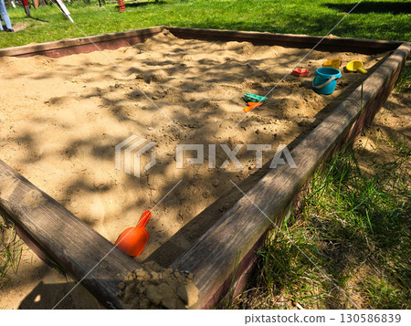 Children Playing in Backyard Sandbox with Colorful Toys 130586839
