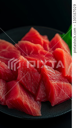 Freshly cut tuna sashimi slices arranged on a black plate  130587029