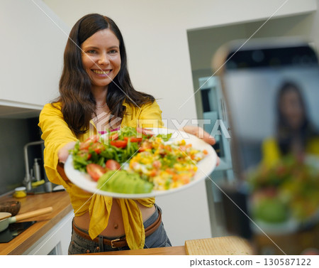 Young woman is broadcasting live from workshop how to prepare a vegetarian food Young woman is broadcasting live from workshop how to prepare a vegetarian food 130587122