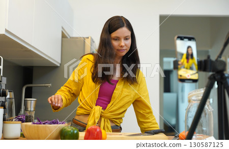 Young woman is broadcasting live from workshop how to prepare a vegetarian food Young woman is broadcasting live from workshop how to prepare a vegetarian food 130587125
